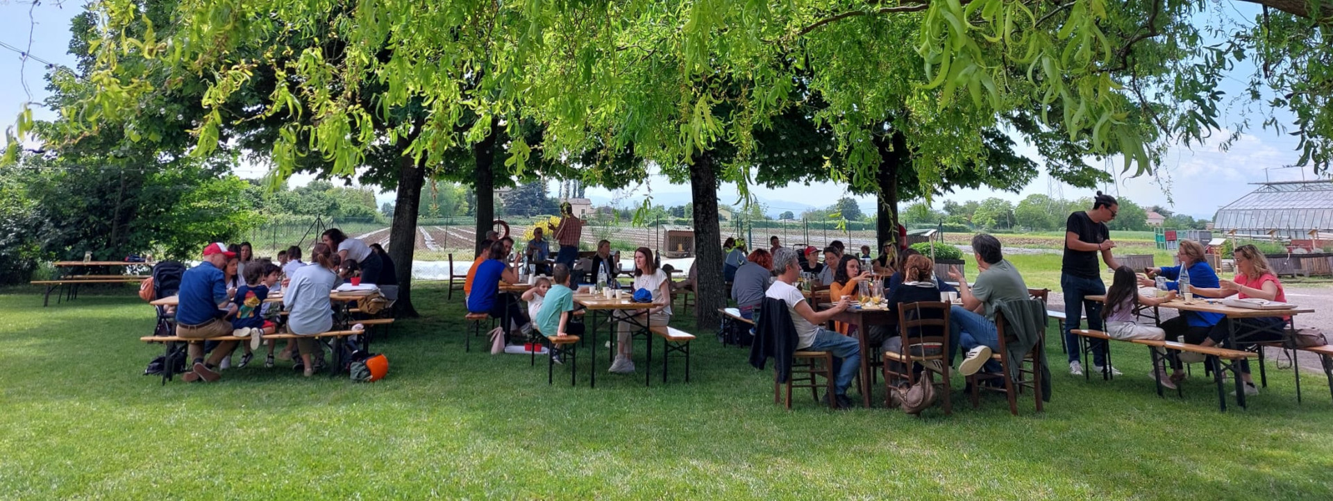 Persone sedute ai tavoli all'aperto nell'Azienda agraria sperimentale Stuard (Parma) - foto Mia Marchini